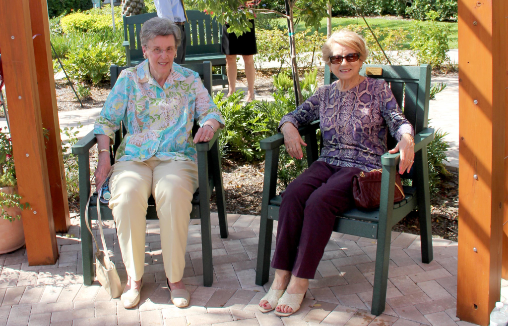 Marcia Eckert and Maria Guadagnino sitting under pergola for Marcia's sister Mary Jo