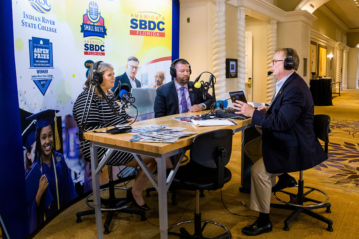 Tom Kindred, right, regional director for Florida SBDC at IRSC, interviews Melissa Roberts, managing director of operations, Jim Moran Institute, and Michael Myhre